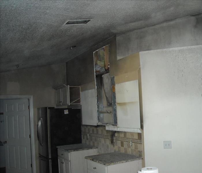 kitchen with white walls, ceiling and cabinets covered in soot damage