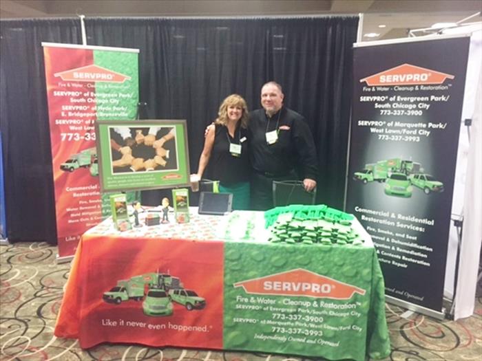 two employees posing behind a table with SERVPRO promotional items