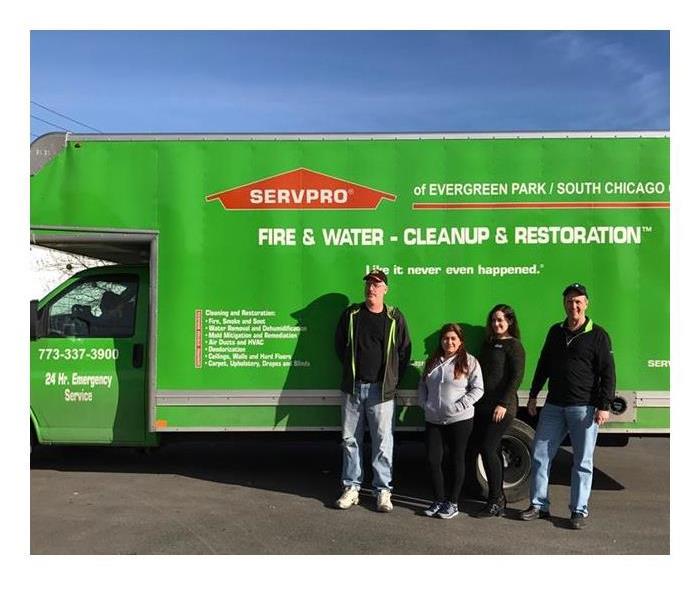 four SERVPRO employees standing in front of a green SERVPRO box truck