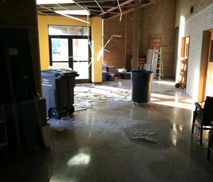 lobby with concrete floor covered in water, debris and two trash cans