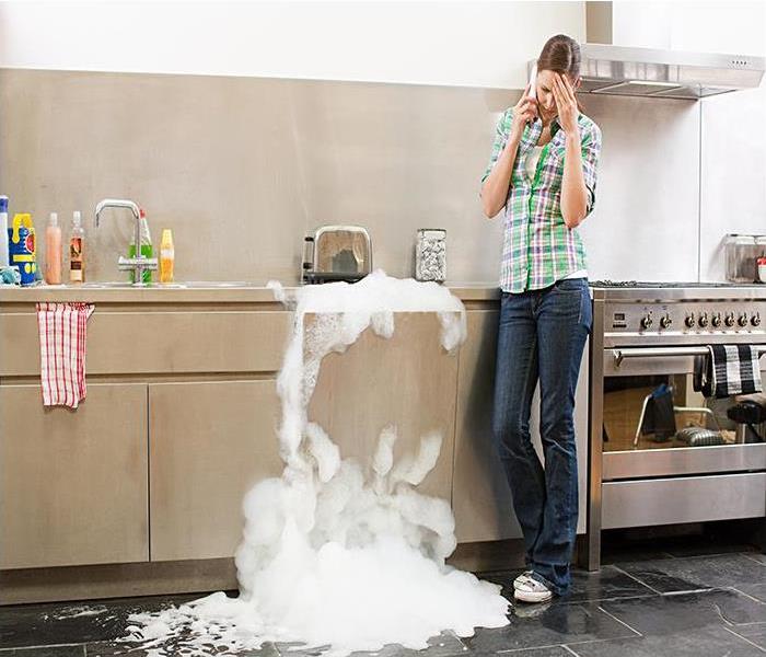female standing next to a sink overflowing with water and soap suds