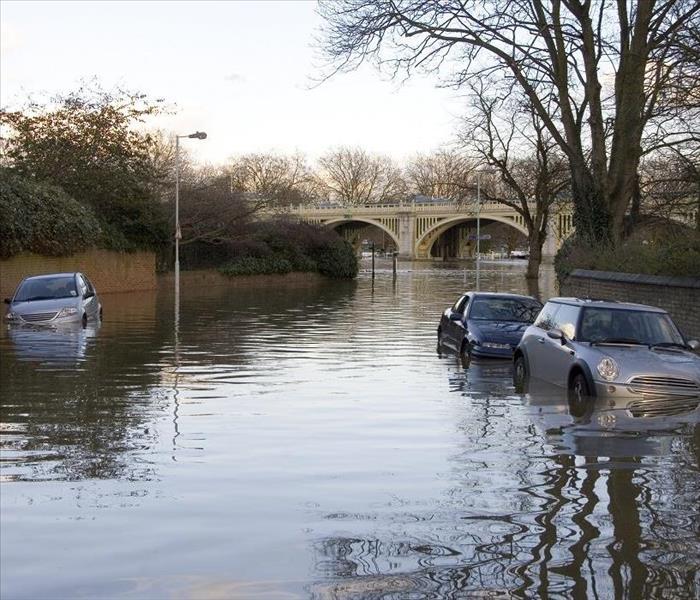 three vehicles submerged in flood waters near a bridge